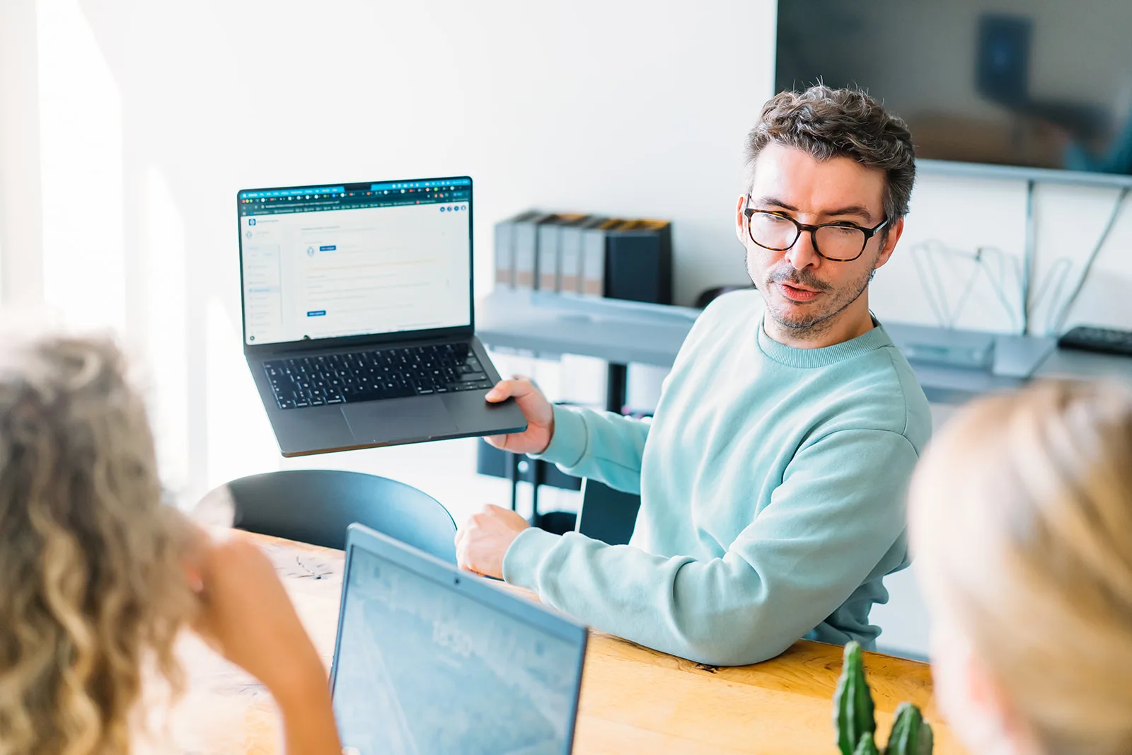 Een werkoverleg bij Userinterface, met een digitale toepassing op een laptop in gesprek met twee deelnemers.